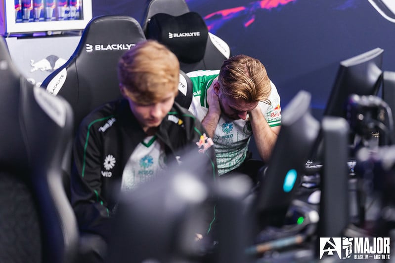 Falcons Counter-Strike players NiKo and mONESY mourn their loss at the Austin Major, sat in front of their computers looking towards the ground with a solemn look on their faces.
