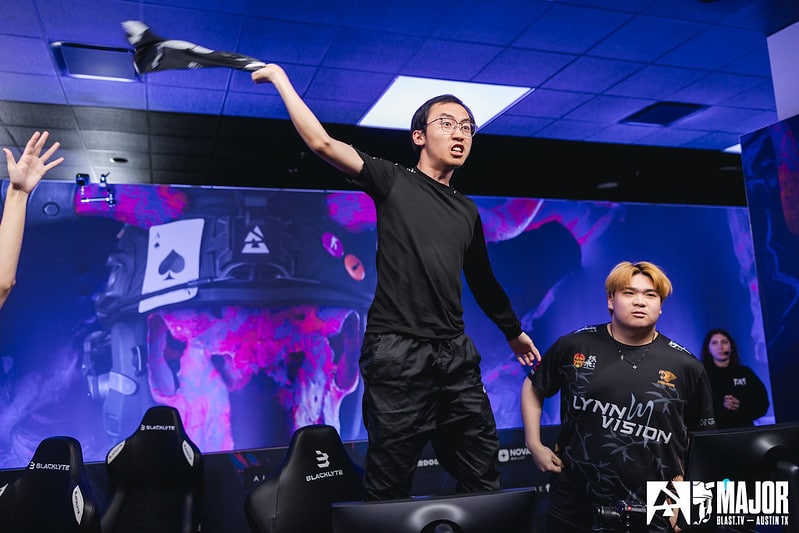 Lynn Vision player EmiliaQAQ celebrates a win by jumping onto the gaming desk and waving his shirt in the air