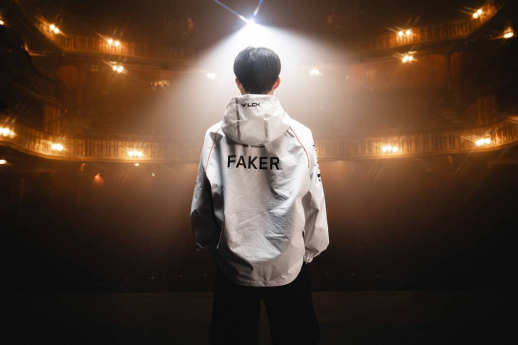 Faker standing facing an empty theatre, wearing a T1 LCK jacket.
