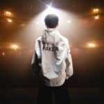 Faker standing facing an empty theatre, wearing a T1 LCK jacket.