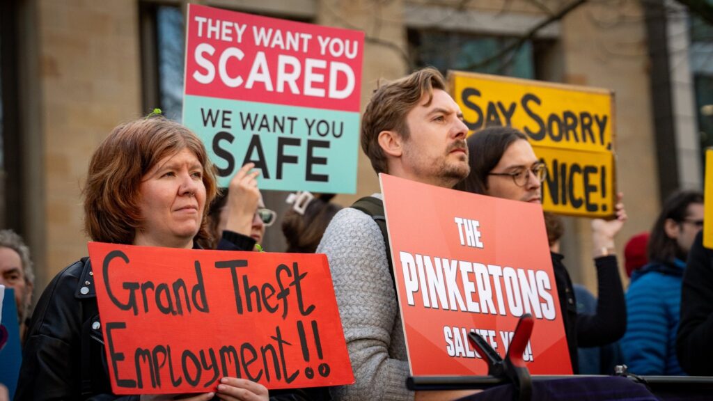 Protesters in Edinburgh campaigning after the controversial Rockstar Layoffs. One protester holds a sign that reads "Grand Theft Employment"