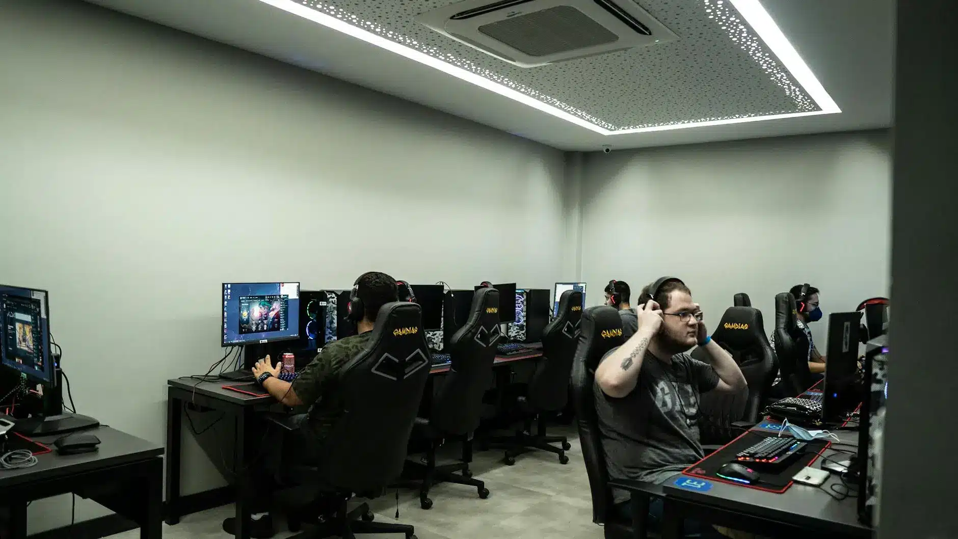Esports players in a modern gaming venue with multiple gaming setups and monitors.