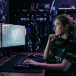 Female esports player in contemplative moment at gaming setup with purple and cyan lighting